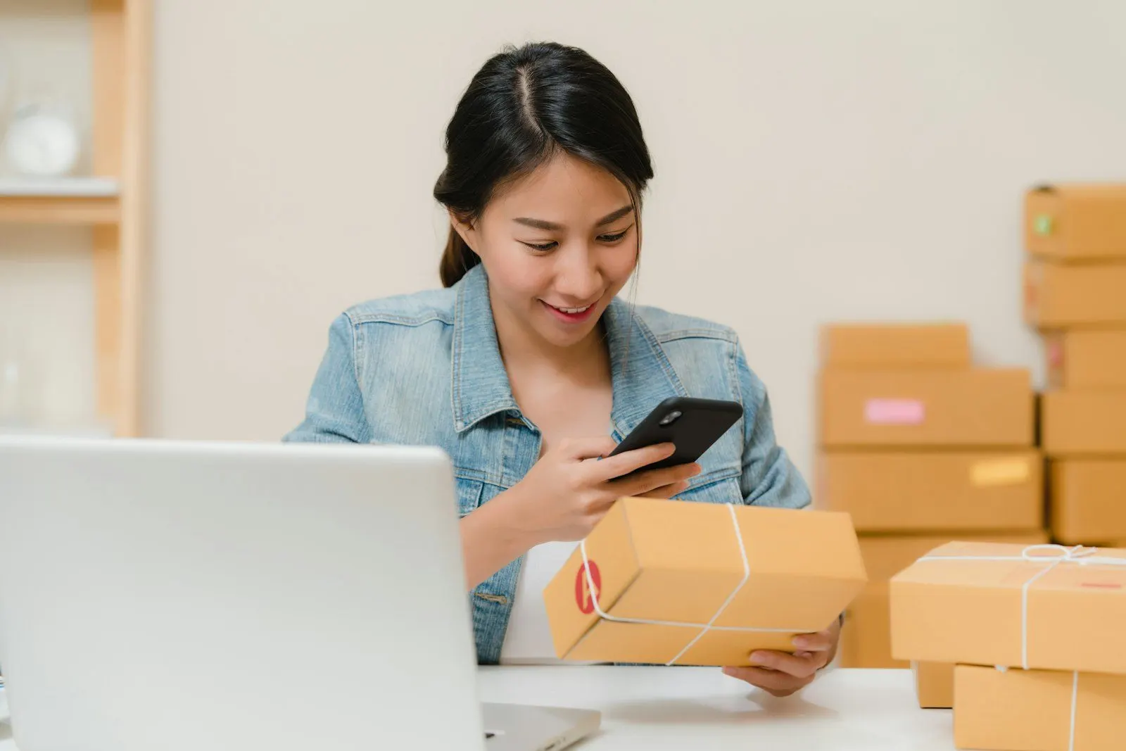 Emprendedora revisando pedidos junto a sus cajas de envío