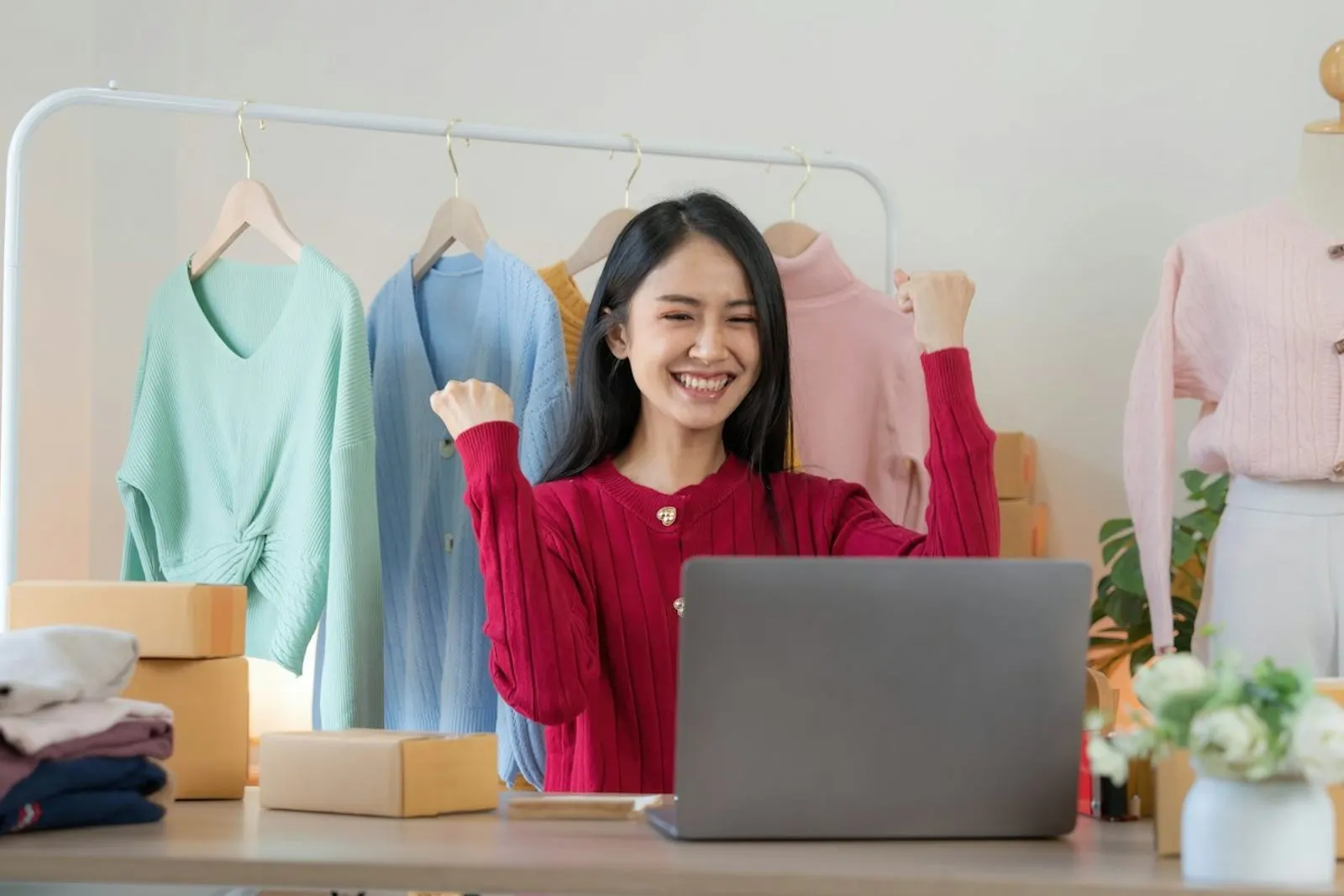 Vendedora en su tienda con la computadora y cajas de pedidos