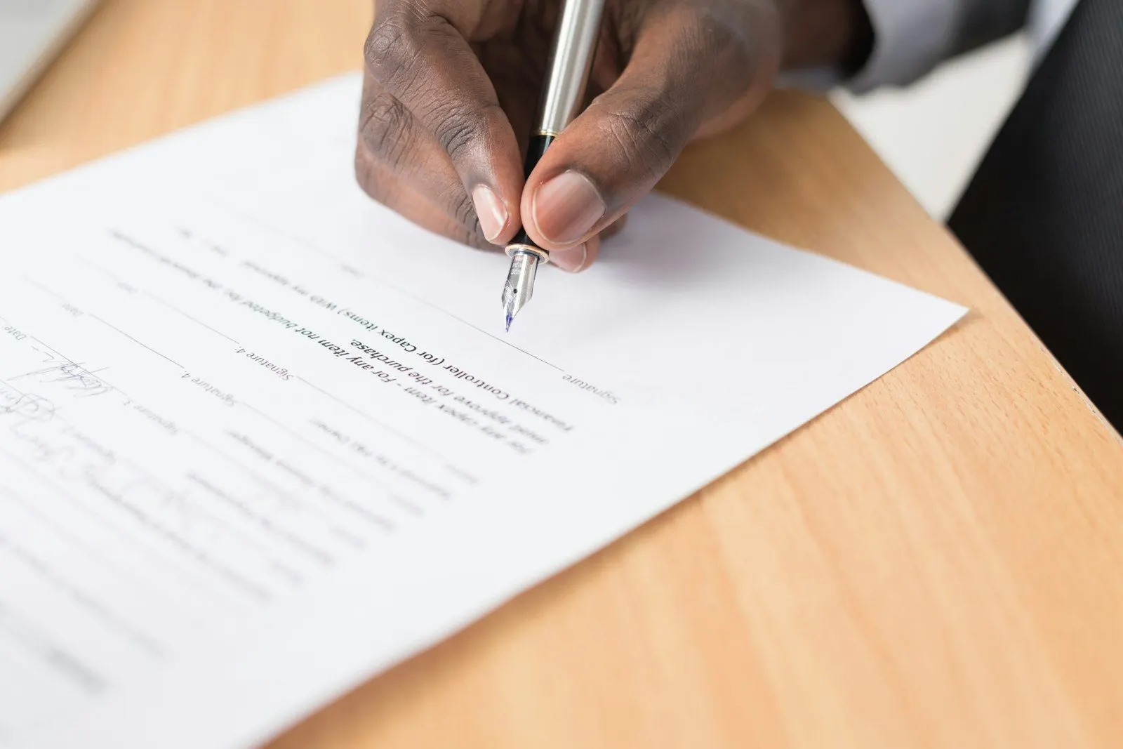 Mano firmando un documento sobre la mesa